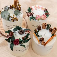 three candles decorated with flowers and pine cones