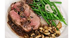 a white plate topped with meat, mushrooms and green beans