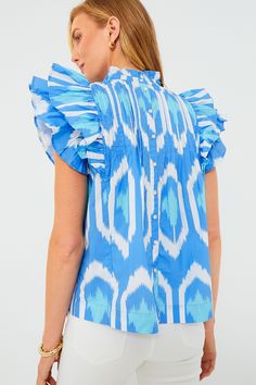 Oliphant's vacation-ready pieces are characterized by breezy silhouettes and vibrant colors.A Tuckernuck exclusive, the Blue Odisha Pintuck Ruffle Top is here to add a bit of drama and oceanic energy to your wardrobe. With statement flutter sleeves, pintucking across the bodice, and buttons down the back, this blouse will quickly become a favorite as an easy silhouette with a whole lot of flair. Style with any color of denim for a quick throw-on-and-go look which is effortless but looks cool as Breezy Summer Blouse With Ruffles, Summer Breezy Blouse With Ruffles, Summer Ikat Print Tops, Blue Ikat Print Top For Summer, Blue Bohemian Blouse With Ruffle Sleeves, Bohemian Blue Blouse With Ruffle Sleeves, Blue Flutter Sleeve Blouse For The Beach, Blue Ruffle Sleeve Tops For Vacation, Blue Ruffles Blouse For Summer