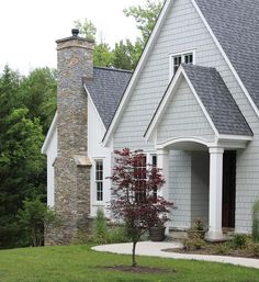 a gray house with a red tree in the front yard