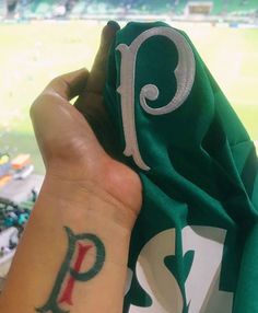 a person with a tattoo on their arm holding up a green shirt at a baseball game