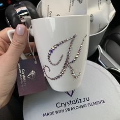 a hand holding a coffee mug with some beads on it and a name tag attached to the cup