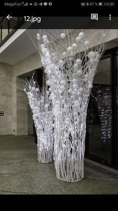 two tall white vases sitting on top of a floor next to each other in front of a building