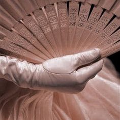 a person in white gloves holding a fan