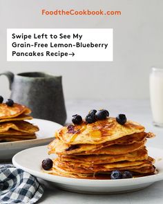 a stack of pancakes with blueberries is on a plate next to a glass of milk