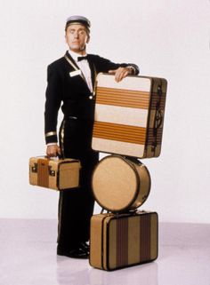 a man in a tuxedo holding two suitcases