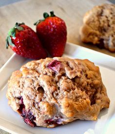 two strawberry muffins on a white plate with strawberries