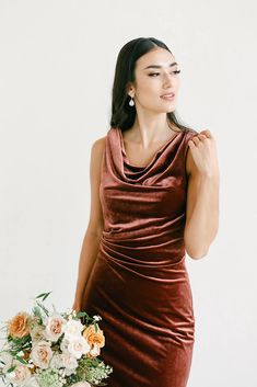 a woman in a brown dress holding a bouquet