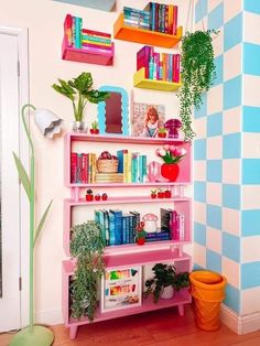 a pink shelf with books and plants on it