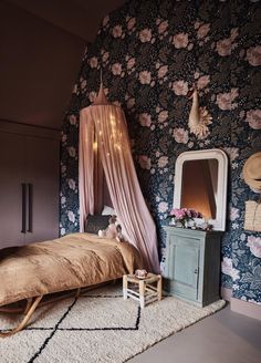 a bedroom with floral wallpaper and a canopy bed in front of a mirror on the wall