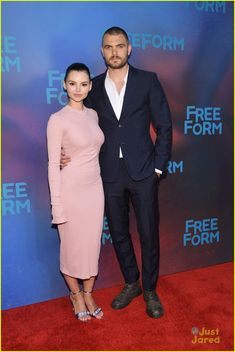 a man and woman standing next to each other in front of a blue wall with the words free form written on it