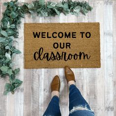 a welcome mat with the words welcome to our classroom on it and a woman's feet in jeans