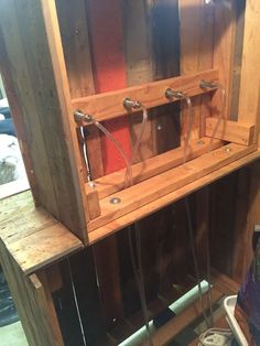 a wooden shelf with wires attached to it in a room filled with other wood and metal items