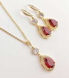 Luxury red ruby cubic zirconia bridal tear drop dangle pendant and necklace in gold plated brass setting. Necklace pendant features a large teardrop with pear cut red ruby cubic zirconia center surrounded by tiny round zirconia crystals and dangles from round cubic zirconia connector and bail. Length of the gold plated chain is 18 inches and comes with 2 inches extender and lobster clasp. For matching earrings click: https://www.etsy.com/listing/667776478/red-crystal-gold-earrings-red-bridal?ref Red Gold-plated Jewelry Set For Wedding, Gold Teardrop Pendant Jewelry Sets As Gift, Teardrop Gold Plated Necklace For Wedding, Gold Plated Teardrop Necklace For Wedding, Gold Cubic Zirconia Teardrop Bridal Necklace, Red Drop Jewelry For Anniversary, Red Gold Plated Necklaces For Wedding, Elegant Red Teardrop Pendant Drop Necklace, Red Teardrop Jewelry For Anniversary