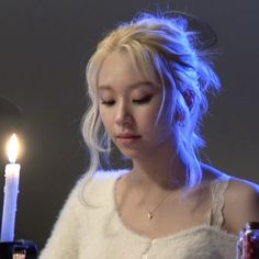 a woman looking at her cell phone in front of a lit candle