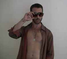 a shirtless man wearing sunglasses is holding his cell phone up to his eyeglasses