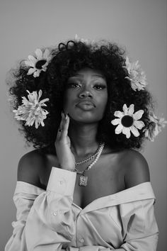 a black and white photo of a woman with flowers in her hair, wearing an off the shoulder dress