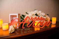 a couple of candles sitting on top of a table next to some flowers and pictures