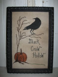 a black crow sitting on top of a tree branch next to a jack o'lantern