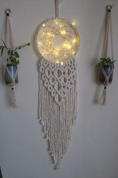 three macrame hangings with lights on them and plants in the middle one