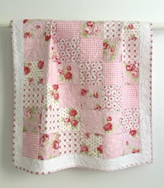 a pink and white quilt hanging on a wall