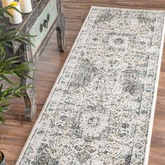 a large rug on the floor in front of a table with candles and potted plants