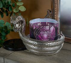 a purple candle sitting on top of a wooden table next to a snake shaped container