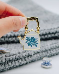 a person is holding a key chain with a teapot on it