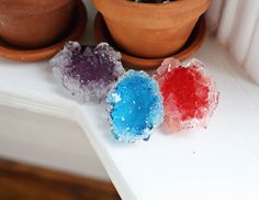 three different colored rocks sitting on top of a white shelf next to a potted plant