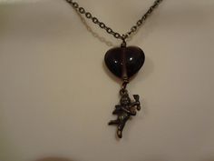 This beautiful vintage glass heart with cupid is suspended on an antiqued brass fine chain. I will make it the length you need (see lengths at checkout).  It is finished with an antiqued brass lobster clasp and adjustable length chain and Swarovski crystal for a versatile fit. Arrives gift boxed with an organza ribbon ready for giving or as a treat to yourself. Shipped domestically via USPS First Class tracked shipping. Vintage Brass Necklace For Valentine's Day, Bronze Heart-shaped Necklace For Valentine's Day, Bronze Heart Necklaces For Valentine's Day, Antique Nickel-free Necklace For Valentine's Day, Antique Brass Necklaces For Valentine's Day, Vintage Bronze Necklaces For Valentine's Day, Vintage Bronze Necklace For Valentine's Day, Vintage Nickel-free Necklace For Valentine's Day, Victorian Brass Necklace For Valentine's Day