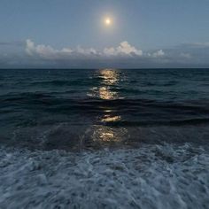 the moon is shining over the ocean water