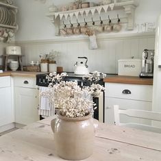 a vase with flowers sitting on top of a wooden table in a kitchen next to an oven