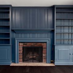 an empty living room with blue bookcases and a fire place in the fireplace