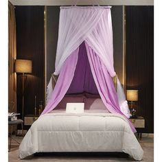 a white bed topped with a purple canopy over it's headboard and pillows