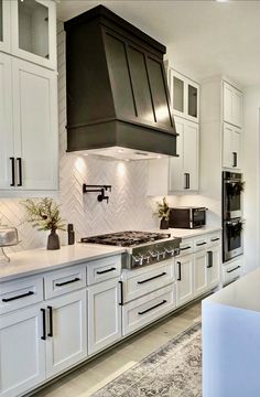 a kitchen with white cabinets and black stove top hood over the range in front of an oven