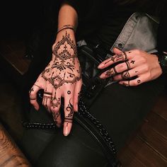 a woman's hands with hennap and tattoos on her hand, sitting down