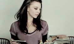 a woman sitting at a table with a plate of food in front of her and looking down