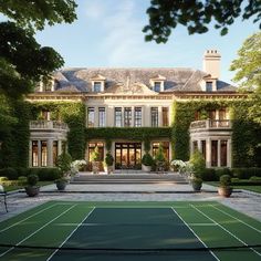 a tennis court in front of a large house with ivy growing on the walls and windows