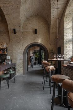 the interior of a brick bar with stools and tables in front of an archway