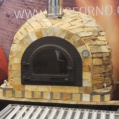 an outdoor brick pizza oven on display in front of a large sign that says,