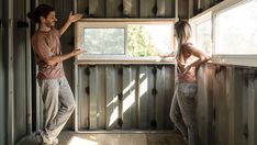 a man and woman standing next to each other in a room with metal siding on the walls