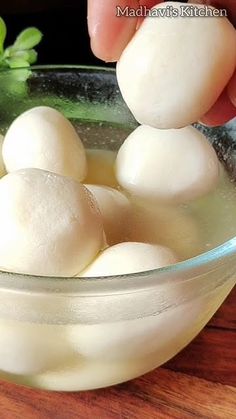 a bowl filled with white balls of food on top of a wooden table next to a plant