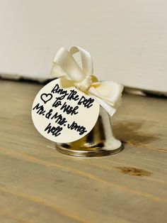 a small metal stand with a white ribbon tied around it on top of a wooden floor