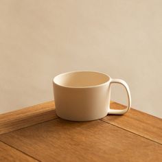 a white cup sitting on top of a wooden table