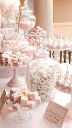 a table topped with lots of candy covered in white and pink candies on top of glass containers