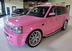 a pink range rover is parked in a showroom