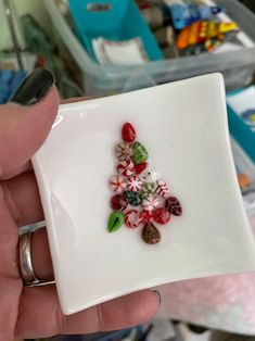 a hand holding a small white plate with candy canes on it