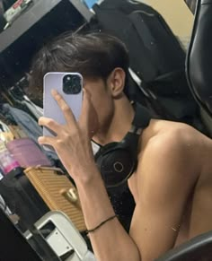 a young man taking a selfie in the mirror with his cell phone while sitting down