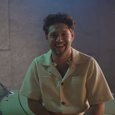 a man smiling while standing next to a green car