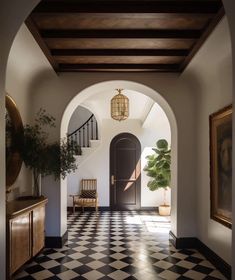 an archway leading into a foyer with black and white checkered flooring, potted plant on the far side